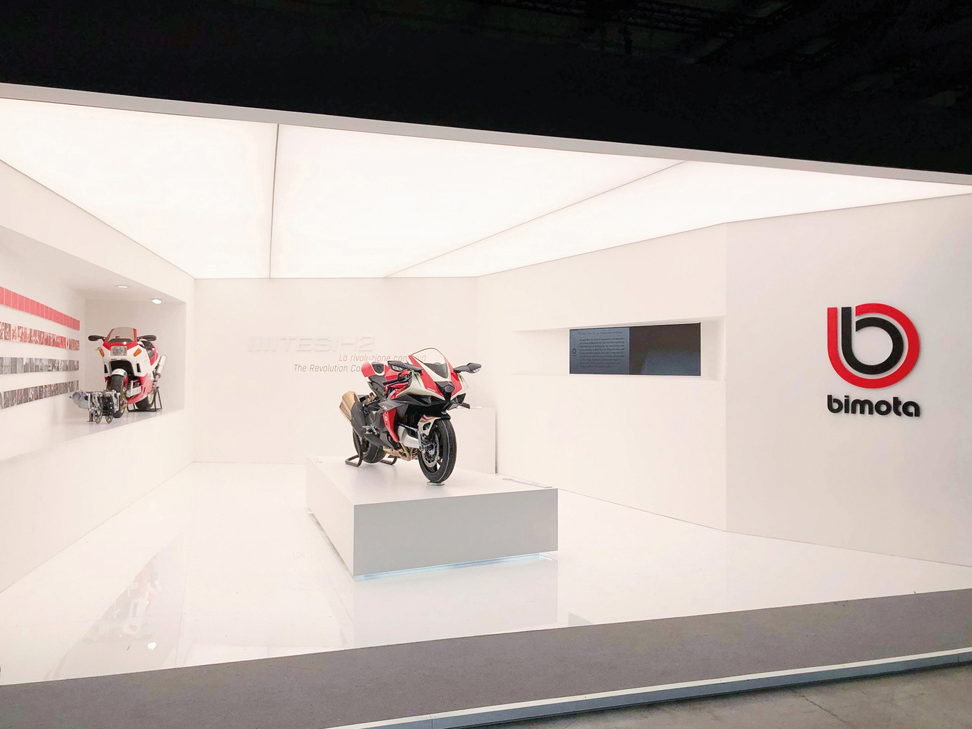 A photo of the Bimota stand at Eicma show 2019 in Milano, showing the all-white interior of the booth with the motorcycle in the middle.