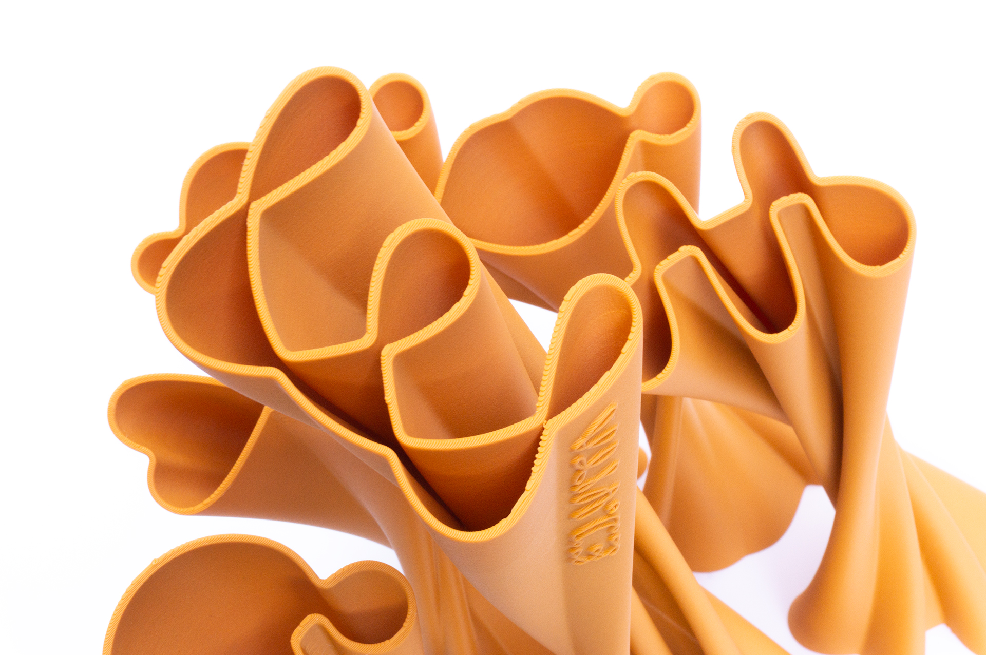 Top view of the ED.VITA trophies arranged in a random pattern, showing clear silhouettes of one large and five smaller trophies, highlighting the elegant extruded logo forms and sustainable PLA-wood material for the Sustainability in Education Award.