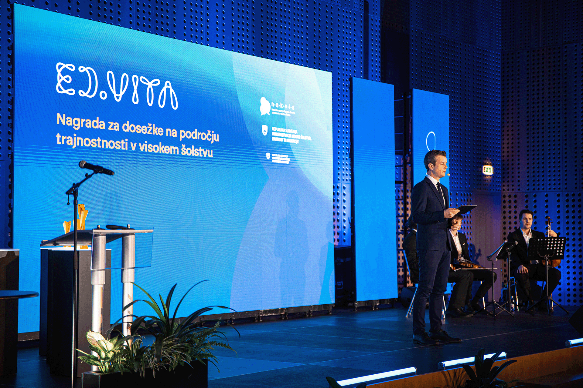 Photo of the ED.VITA national sustainability in education award stage with graphics on the background displays.