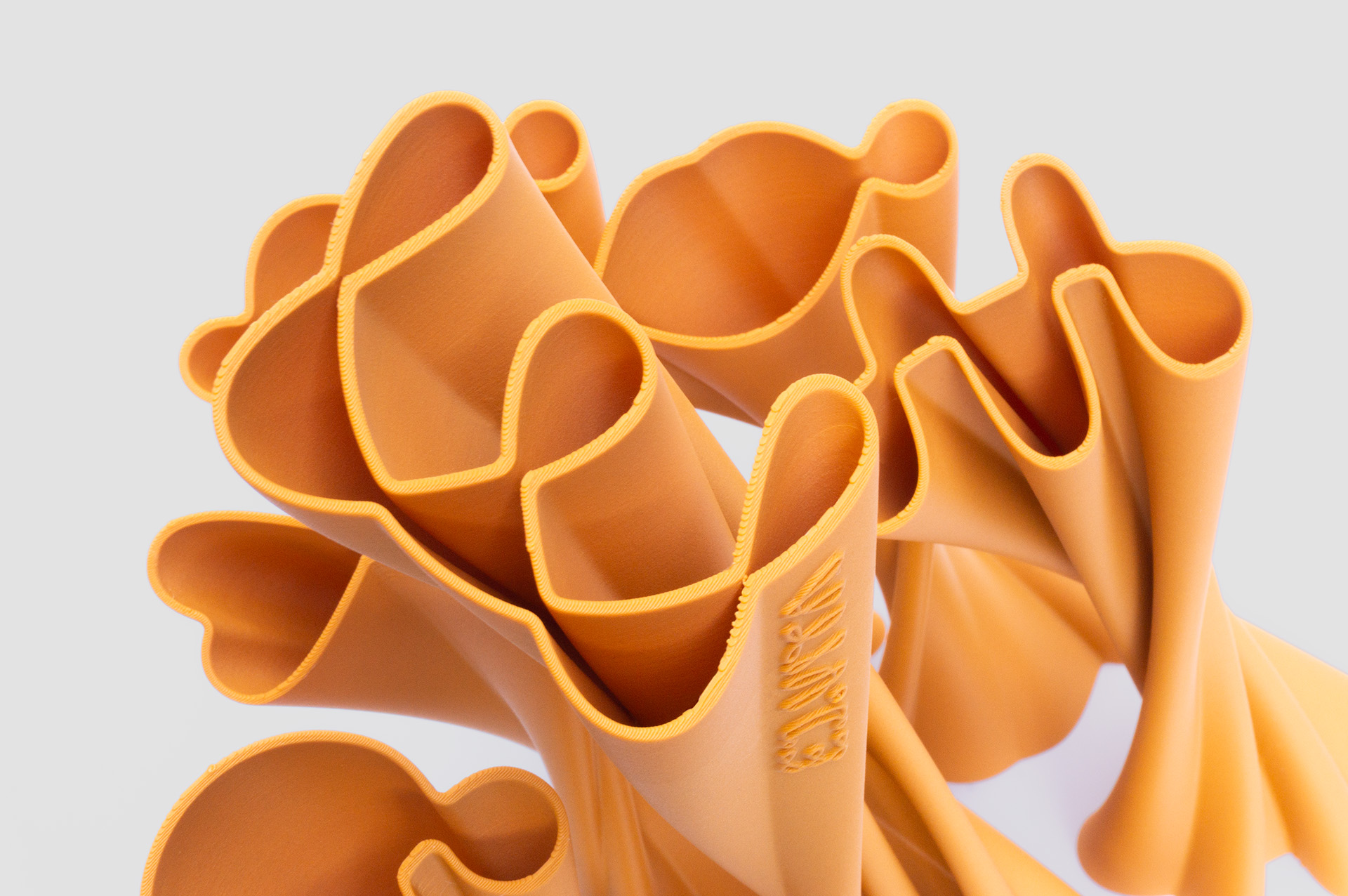 Top view of the ED.VITA trophies arranged in a random pattern, showing clear silhouettes of one large and five smaller trophies, highlighting the elegant extruded logo forms and sustainable PLA-wood material for the Sustainability in Education Award.